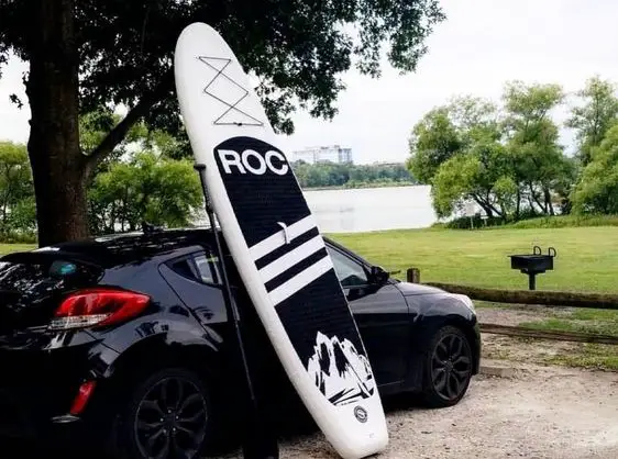 Black ROC inflatable paddleboard leaning against a car